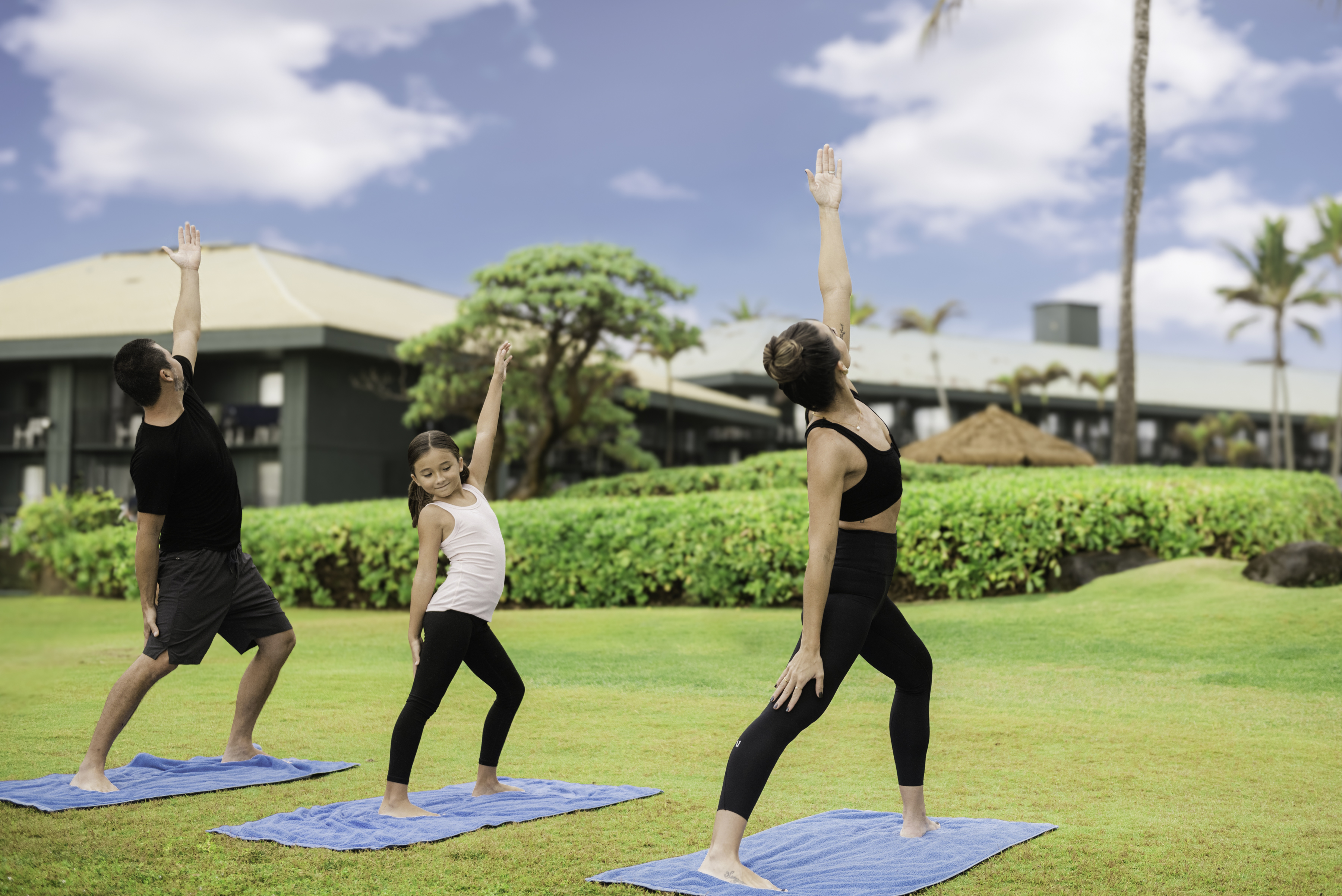 Guests doing yoga on the lawn in front of the beach at OUTRIGGER Kauai Beach Resort & Spa